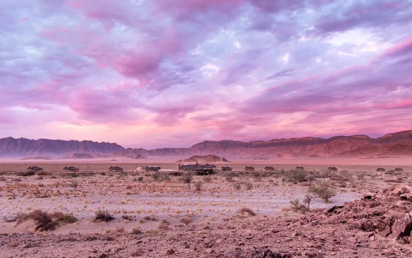 Desert landscape at sunset with scattered acacia trees and mountains, Hoodia Desert Lodge, Sossusvlei, Namibia