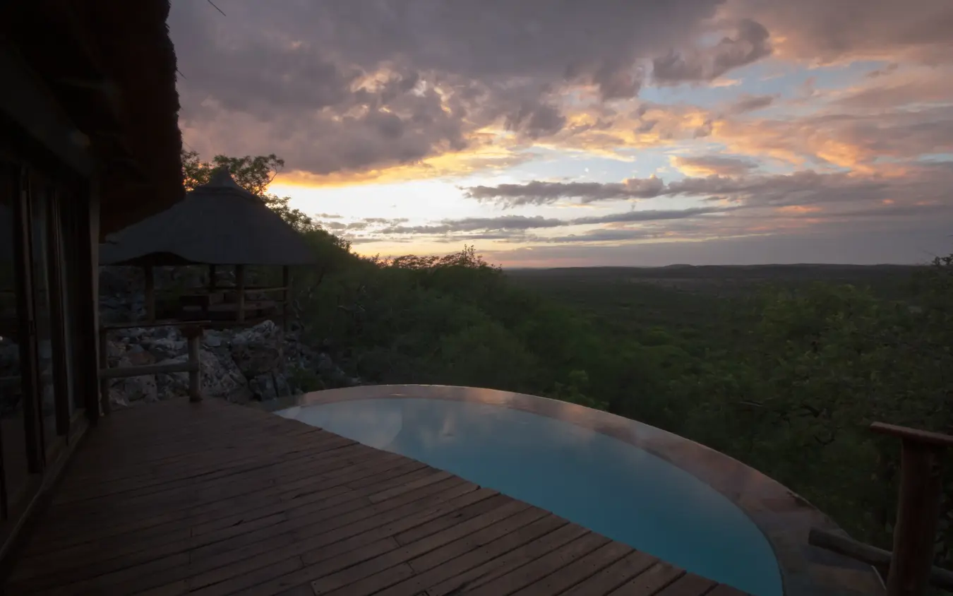 Infinity pool on wooden deck overlooking forested valley at sunset, Horizon by Ongava, Etosha National Park, Namibia