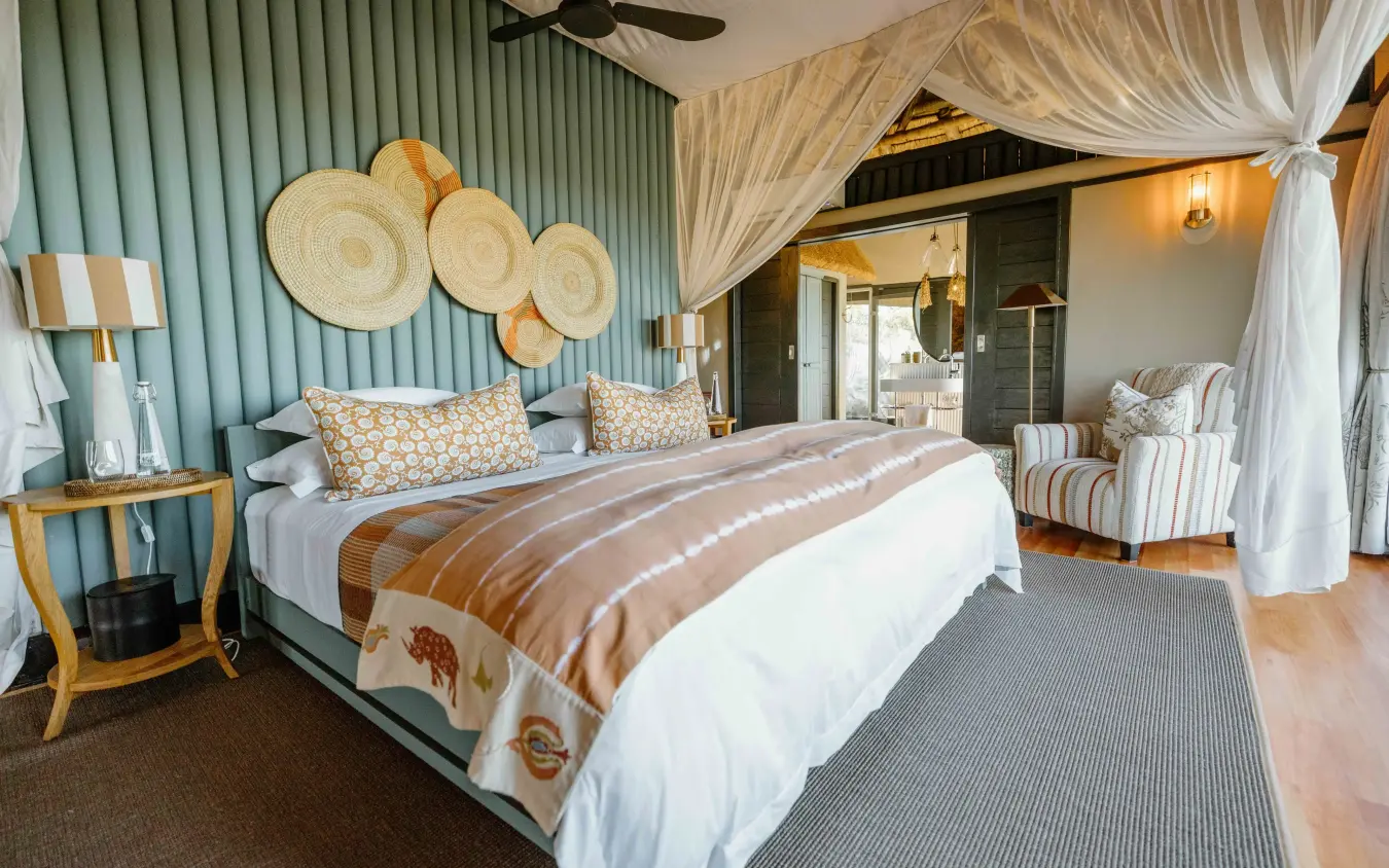 Luxury safari bedroom with canopied bed and savanna views through open doors, Horizon by Ongava, Etosha National Park, Namibia