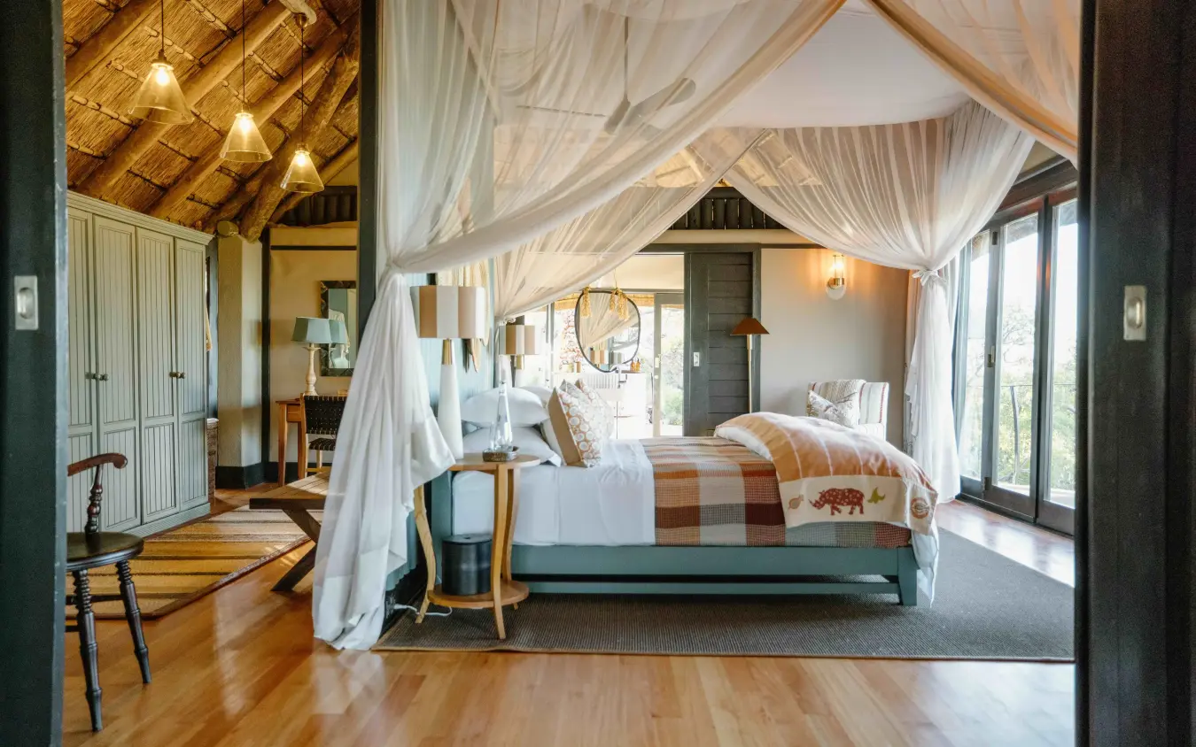 Luxury safari lodge bedroom with sheer canopy drapes and wooden ceiling beams, Horizon by Ongava, Etosha National Park, Namibia