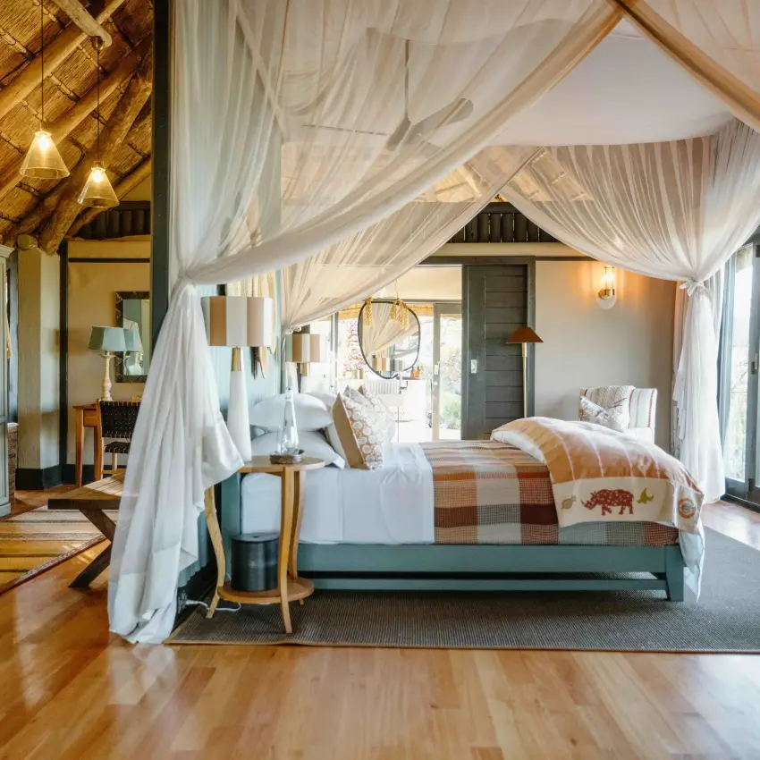 Luxury safari lodge bedroom with sheer canopy drapes and wooden ceiling beams, Horizon by Ongava, Etosha National Park, Namibia