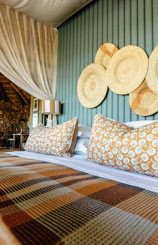 Bedroom interior with woven wall baskets and patterned pillows on bed, Horizon by Ongava, Etosha National Park, Namibia