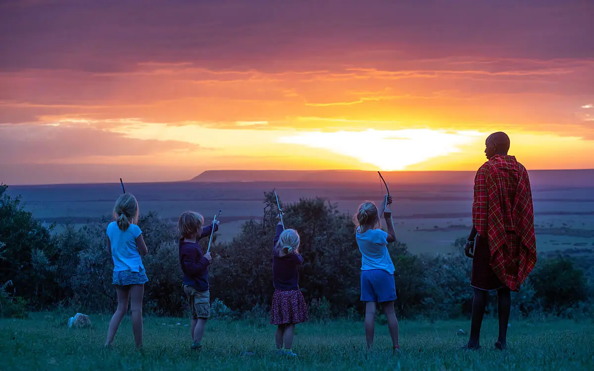 Children with bows and arrows at sunset overlooking plains, House In The Wild, Maasai Mara, Kenya