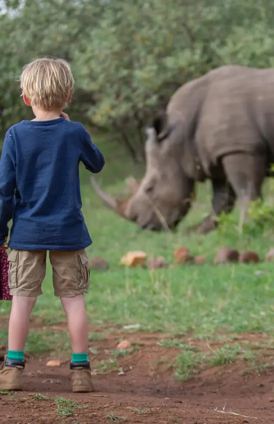 Two children watching elephant grazing in natural habitat, Maasai Mara, Kenya