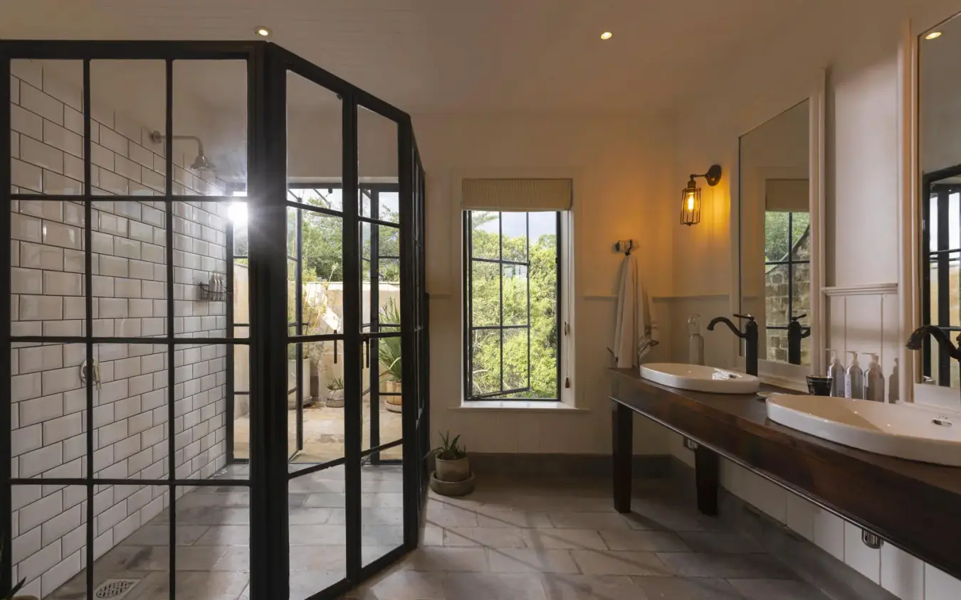 Luxurious bathroom with double vanity and black-framed shower enclosure, House In The Wild, Maasai Mara, Kenya
