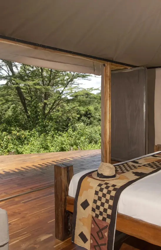 Open-sided bedroom with forest views and wooden deck, House In The Wild, Maasai Mara, Kenya