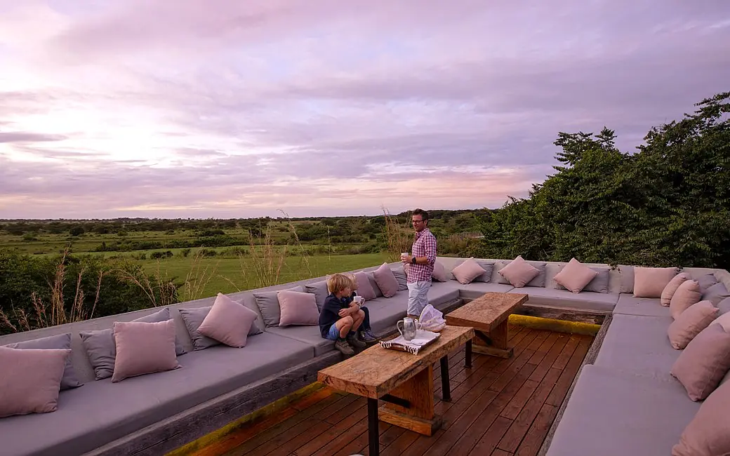 Lounge deck with cushioned seating overlooking savanna at dusk, House In The Wild, Maasai Mara, Kenya