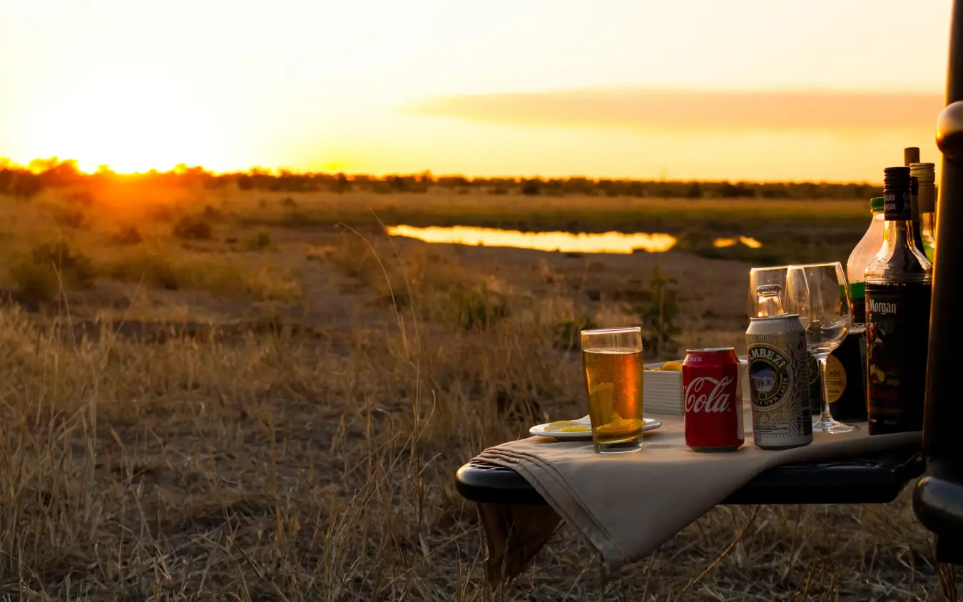 Sundowner drinks setup overlooking savanna waterhole at sunset, Hwange Bush Camp, Hwange National Park, Zimbabwe