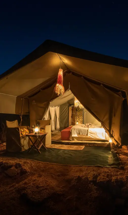 Illuminated canvas safari tent at night in African bush, Hwange Bush Camp, Hwange National Park, Zimbabwe