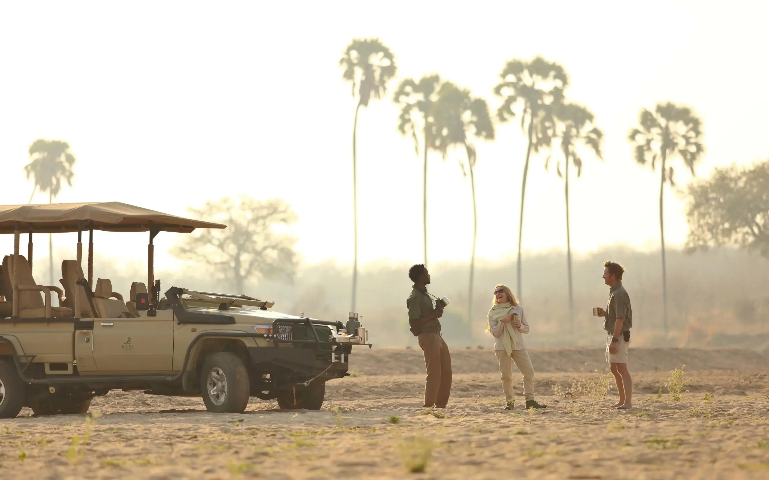 Safari vehicle and guides with tourists in savanna landscape, Ikuka Safari Camp, Ruaha National Park, Tanzania