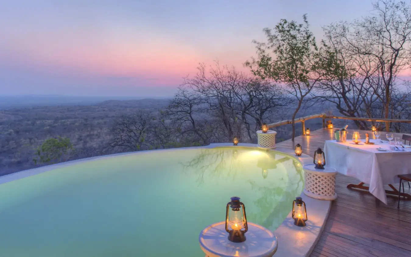 Infinity pool overlooking savanna landscape at sunset, Ikuka Safari Camp, Ruaha National Park, Tanzania