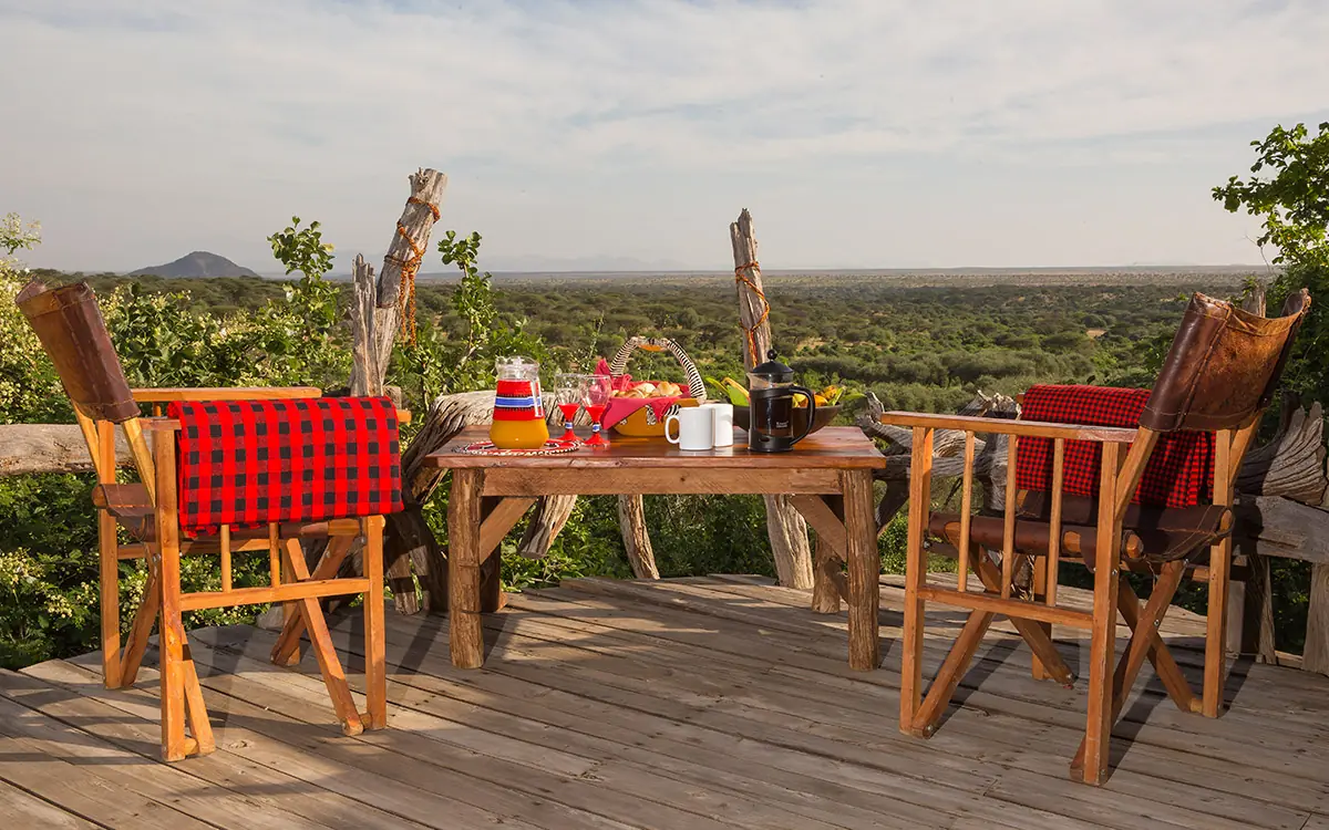Wooden deck dining setup overlooking savanna landscape, Il Ngwesi, Laikipia Highlands, Kenya