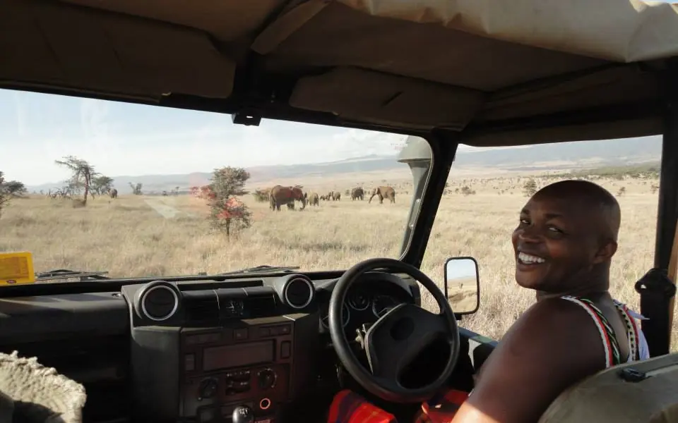 Guest smiling from safari vehicle during game drive, Il Ngwesi, Laikipia Highlands, Kenya