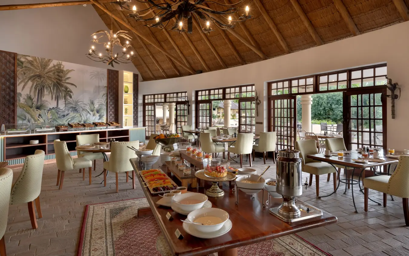Elegant dining pavilion with wooden ceiling and glass doors opening to grounds, Ilala Lodge Hotel, Victoria Falls, Zimbabwe