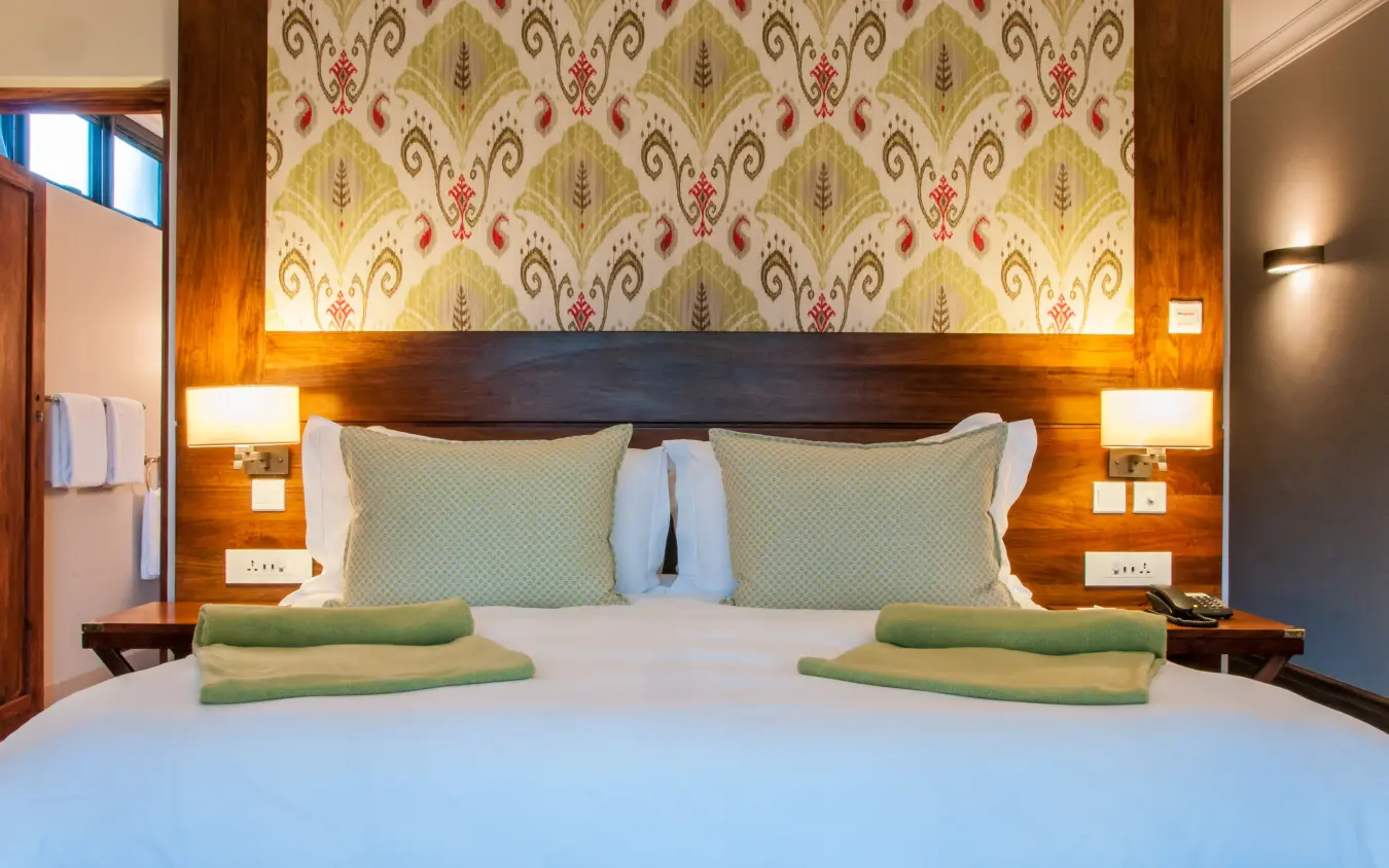 Luxury bedroom with patterned headboard and green accent towels, Ilala Lodge Hotel, Victoria Falls, Zimbabwe