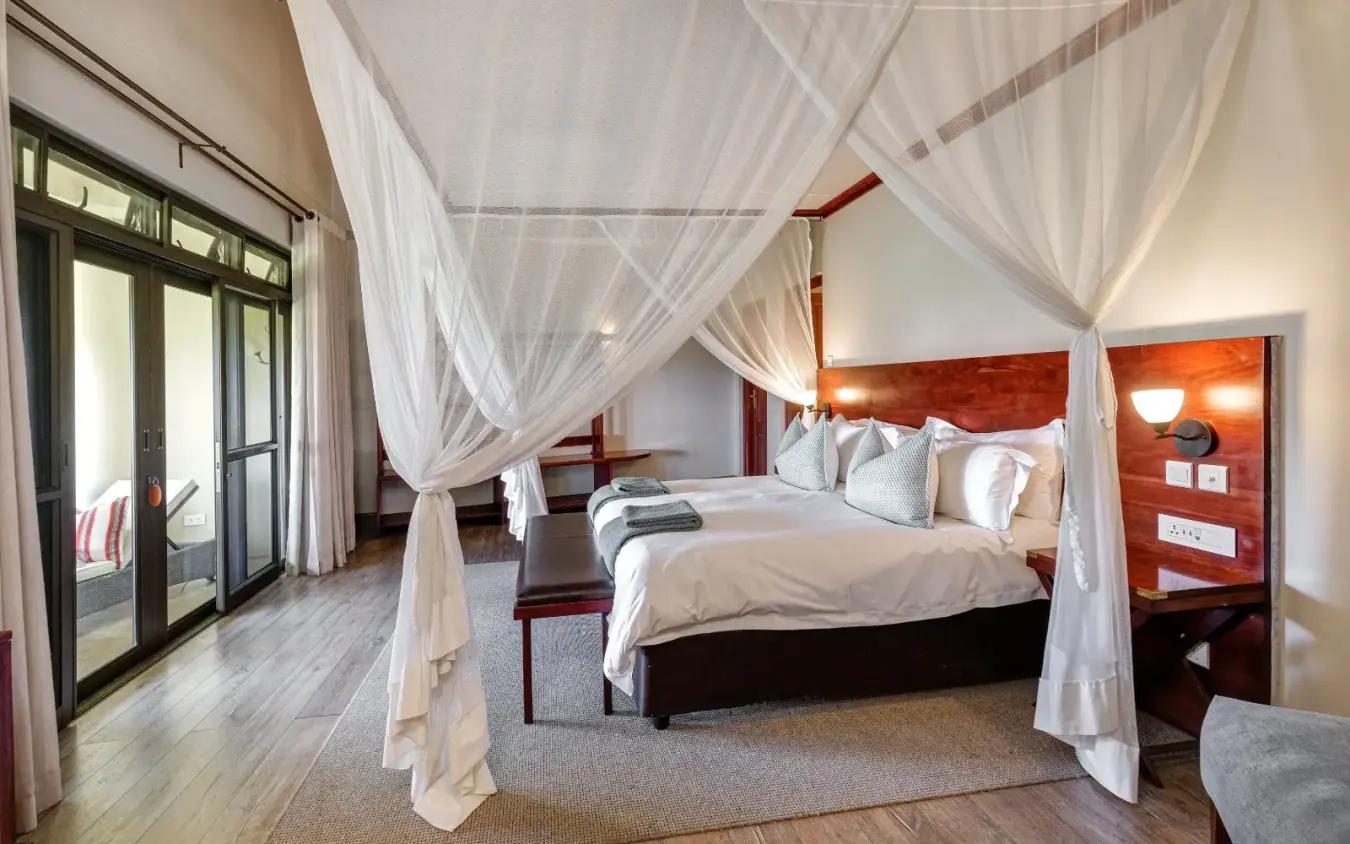 Four-poster canopy bed in luxury safari lodge bedroom with wooden headboard, Ilala Lodge Hotel, Victoria Falls, Zimbabwe