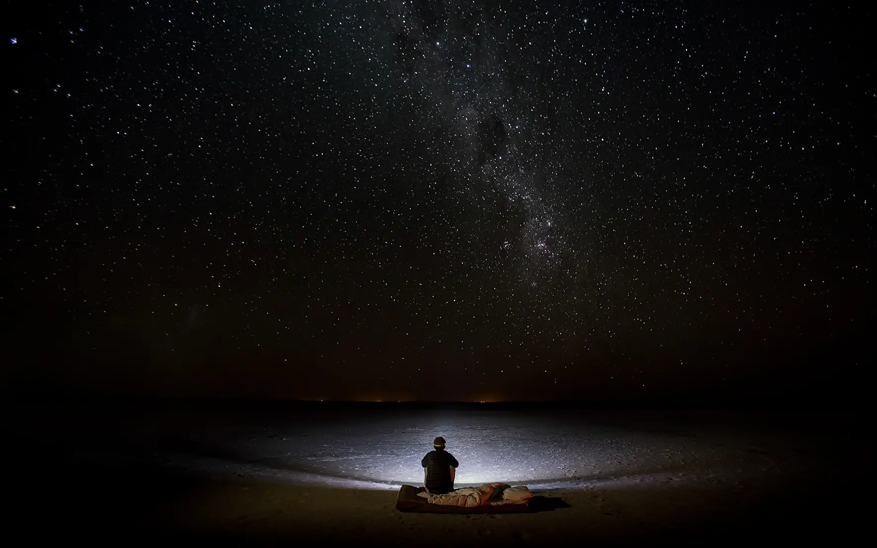 Person sitting alone under starry night sky, Botswana
