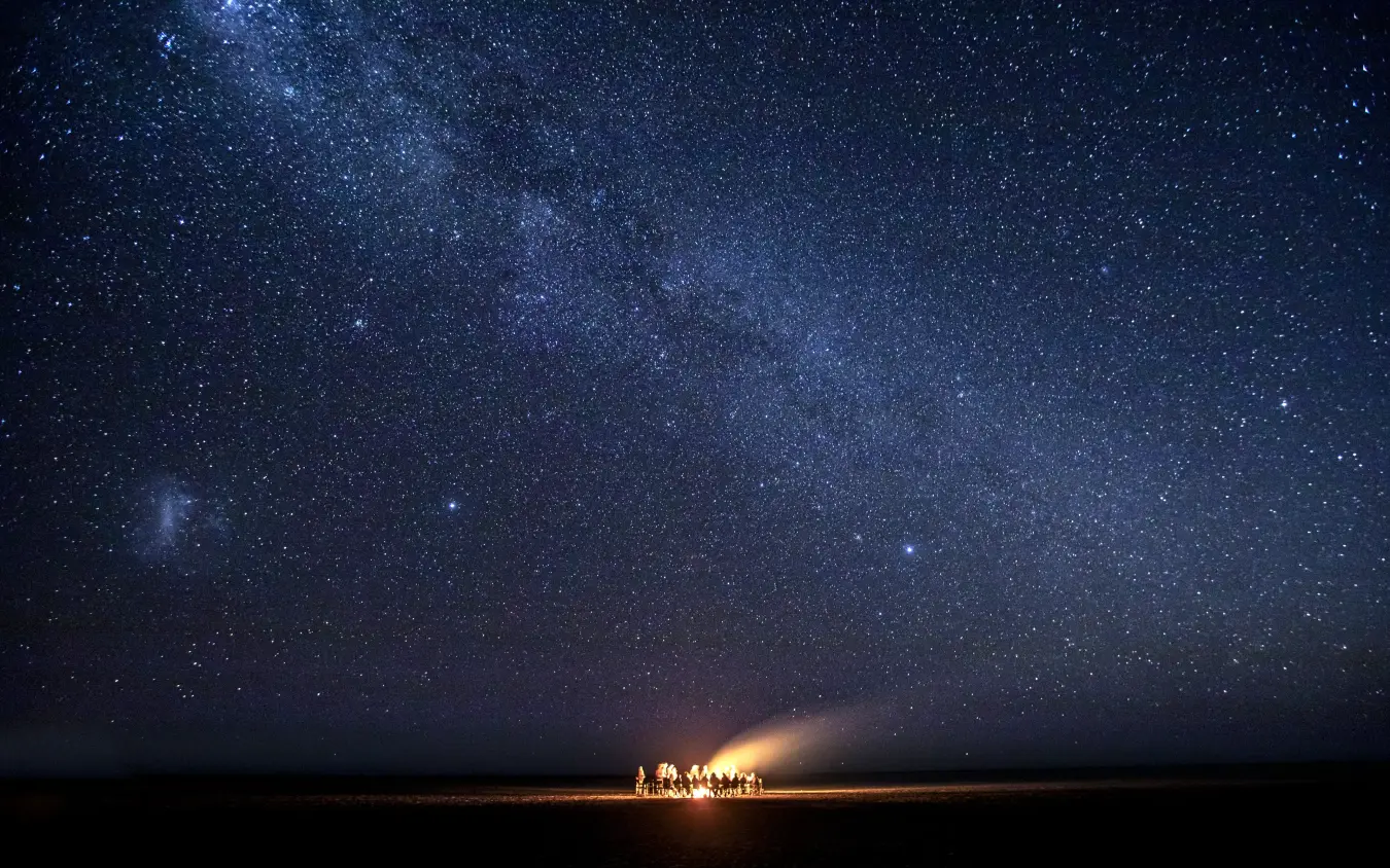 Group gathered around campfire under starry night sky, Jack’s Camp, Makgadikgadi Pans, Botswana