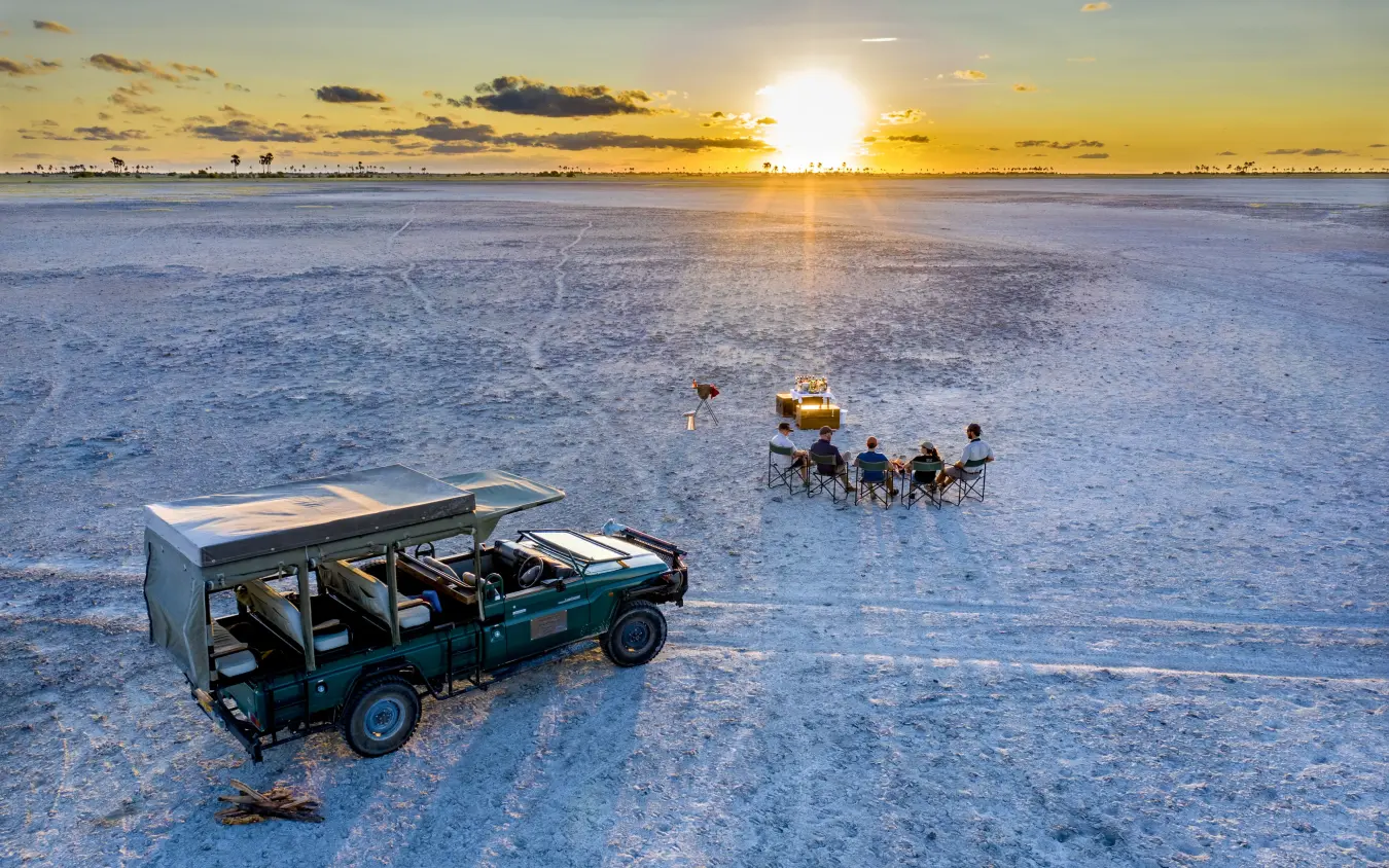 Vehicle and guests dining on salt pan at sunset, Jack’s Camp, Makgadikgadi Pans, Botswana