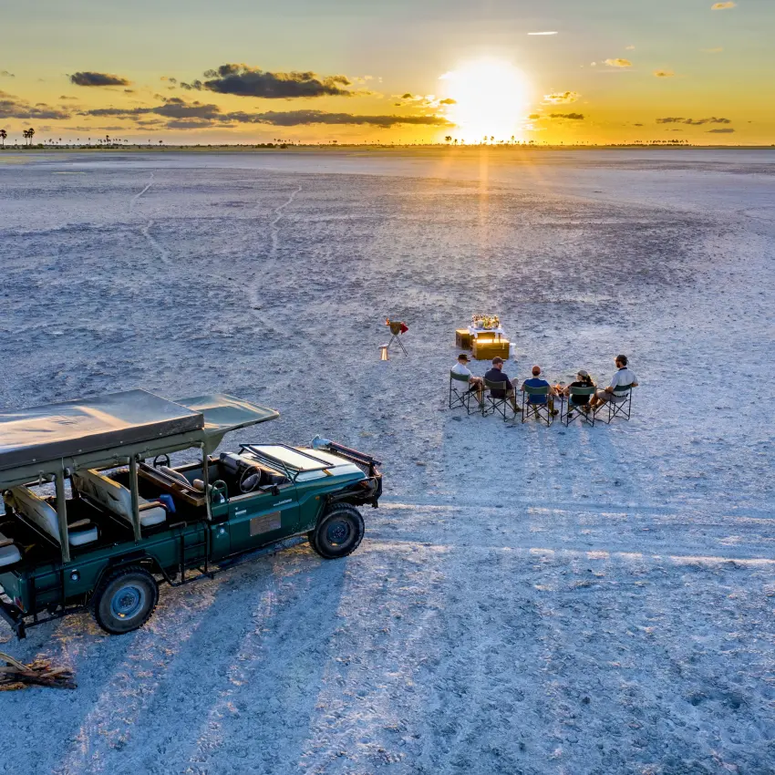 Vehicle and guests dining on salt pan at sunset, Jack’s Camp, Makgadikgadi Pans, Botswana