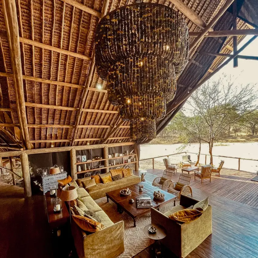 Open-air lodge lounge with fireplace overlooking river and savanna woodland, Jongomero Bush Manor, Ruaha National Park, Tanzania