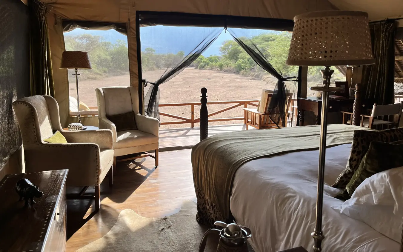 Safari tent interior with bed and seating overlooking savanna landscape, Jongomero Bush Manor, Ruaha National Park, Tanzania