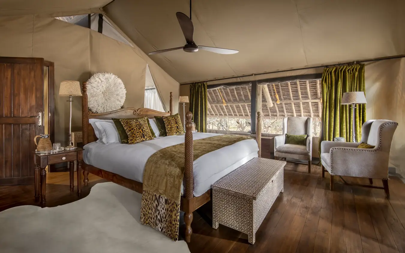 Luxury bedroom with four-poster bed and savanna views through large windows, Jongomero Bush Manor, Ruaha National Park, Tanzania