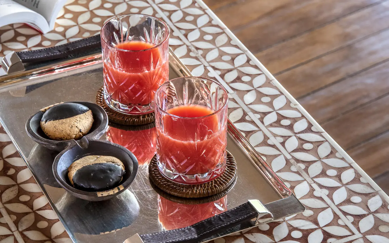 Red juice beverages with cookies and condiments on wooden table, Jongomero Camp, Ruaha National Park, Tanzania