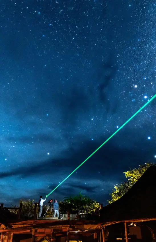Green laser beam pointing at starry night sky, Central Kalahari, Botswana
