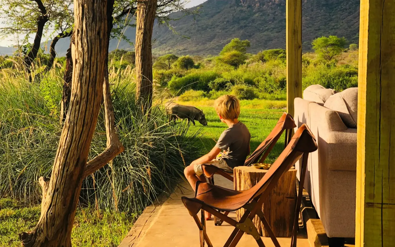 Guest relaxing on deck overlooking savanna and mountains, Kalepo Camp, Northern Kenya, Kenya