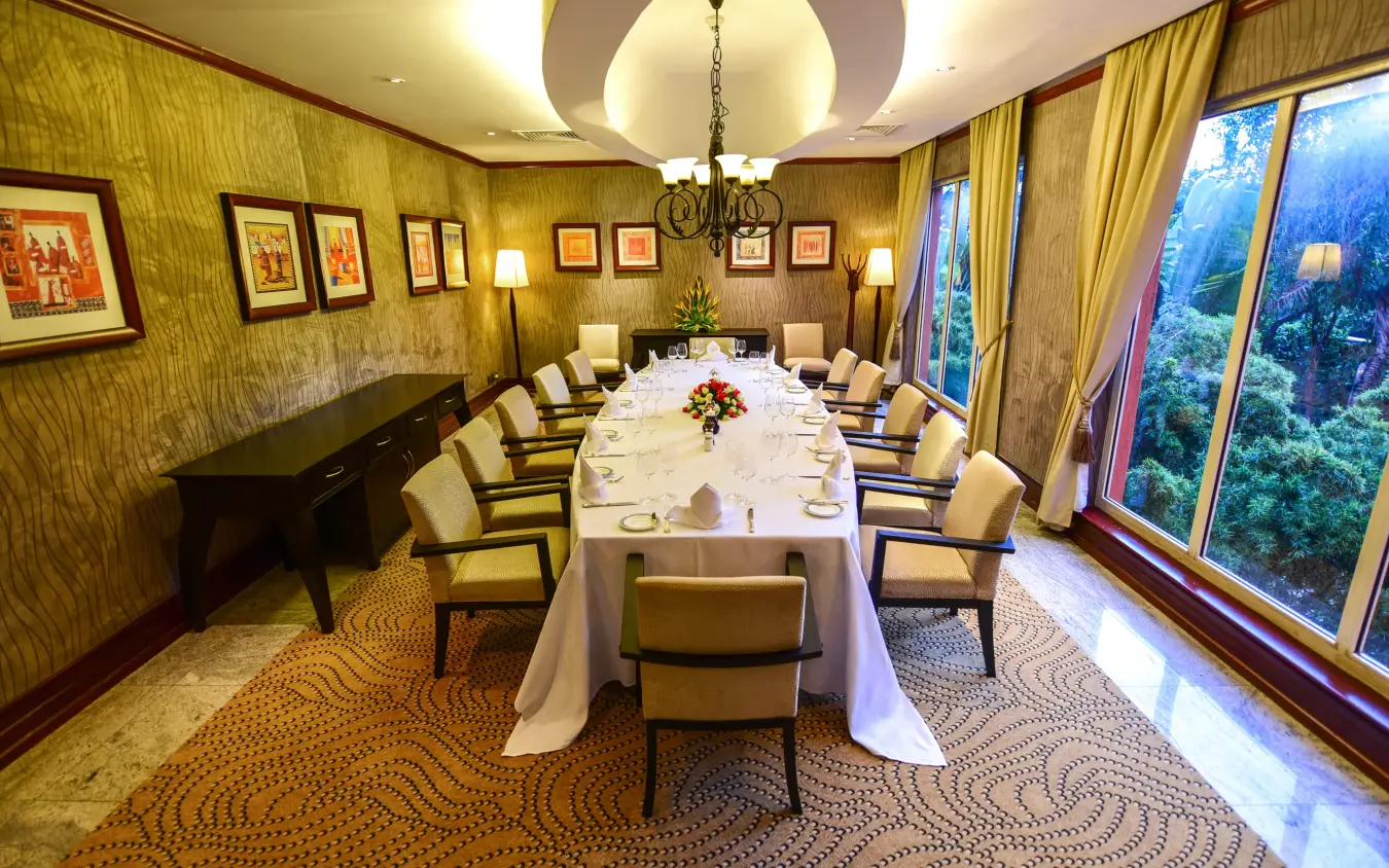 Formal dining room with long table overlooking forested valley through large windows, Kampala Serena Hotel, Entebbe and Kampala, Uganda