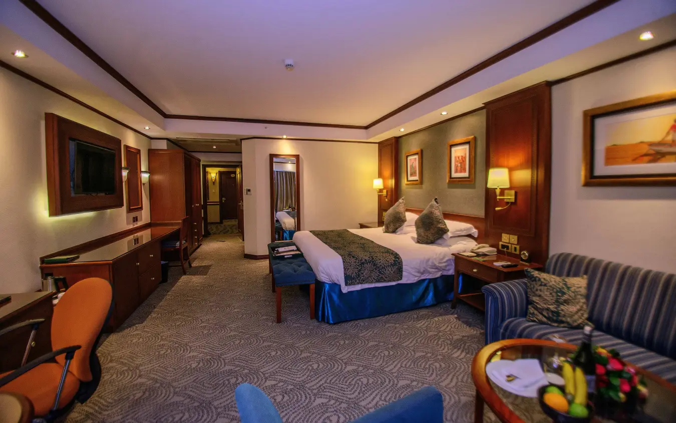 Luxury hotel suite with king bed and modern wood furnishings, Kampala Serena Hotel, Entebbe and Kampala, Uganda