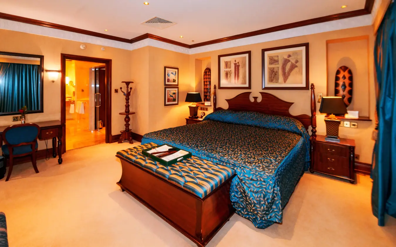 Luxury bedroom suite with blue and gold décor and wooden furnishings, Kampala Serena Hotel, Entebbe and Kampala, Uganda