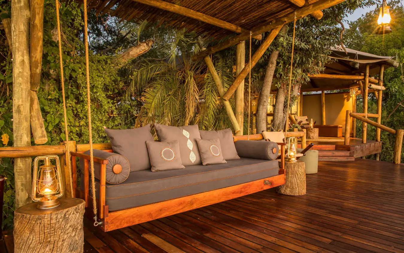 Wooden deck with suspended daybed and tropical vegetation, Kanana, The Okavango Delta, Botswana