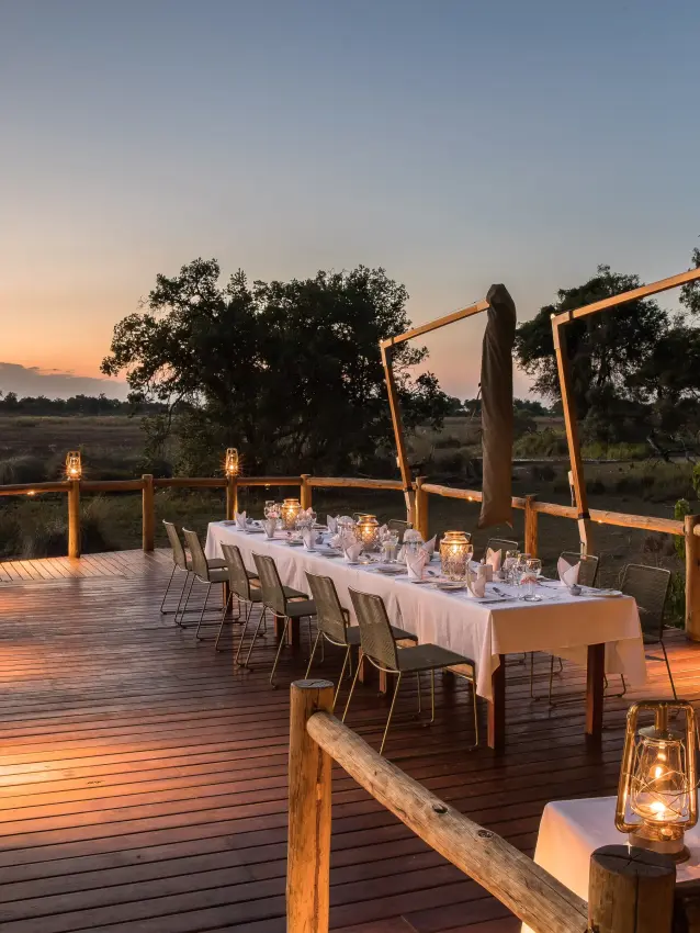 Wooden deck dining setup overlooking savanna at sunset, Kanana, The Okavango Delta, Botswana