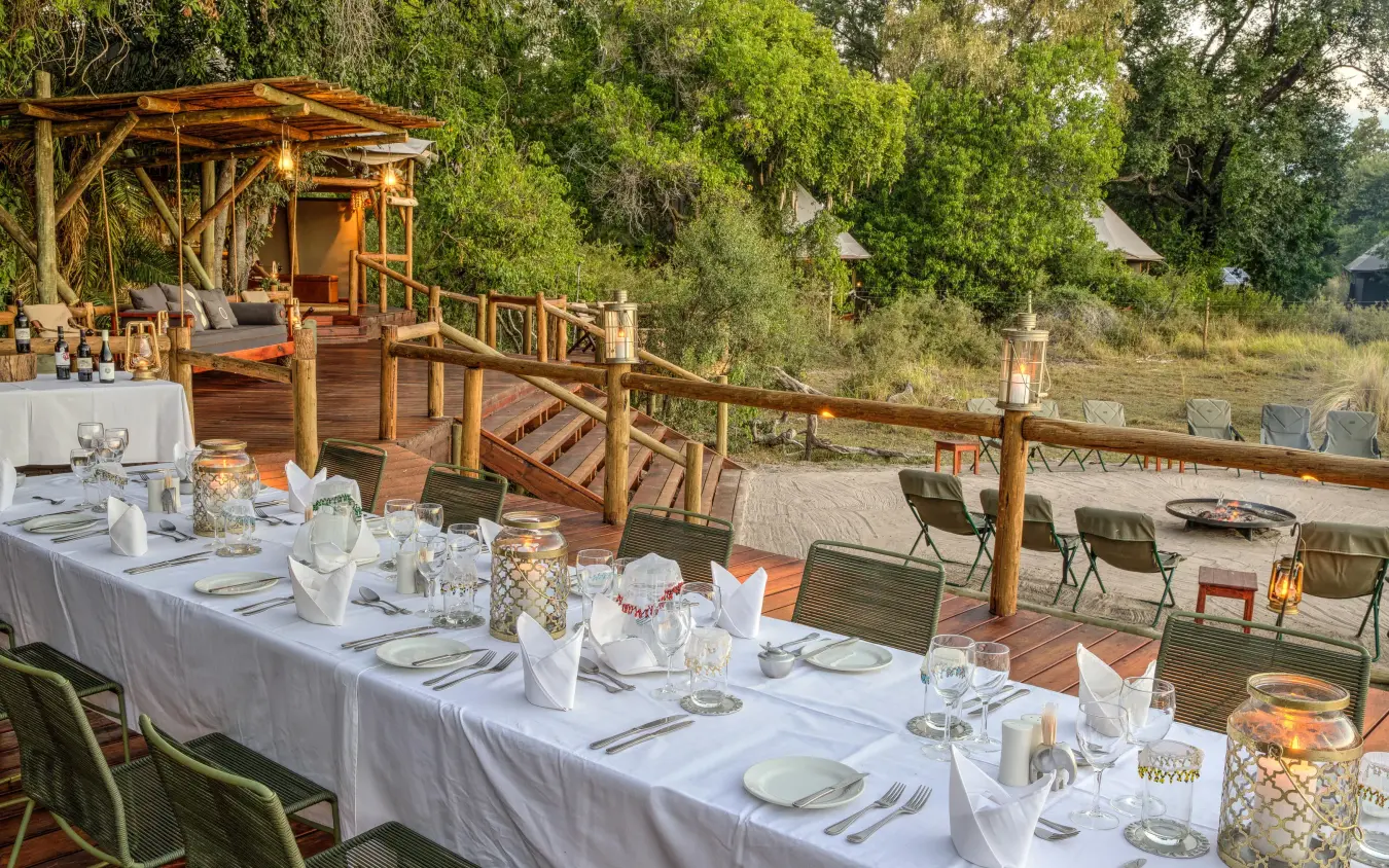 Long dining table set for outdoor meal with river view, Kanana, The Okavango Delta, Botswana