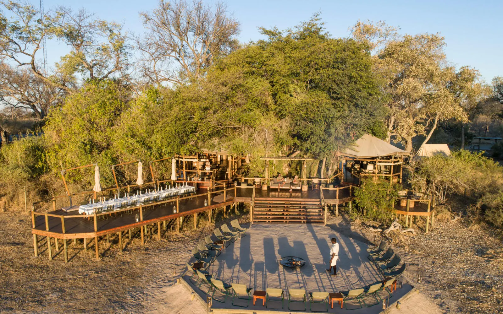 Wooden deck and seating areas beneath acacia trees, Kanana, The Okavango Delta, Botswana