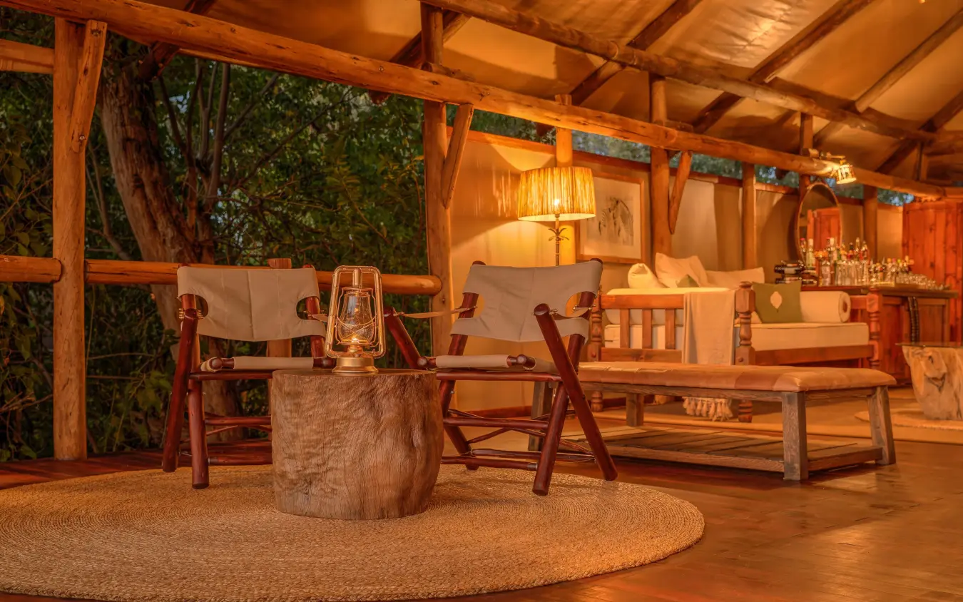 Wooden lodge interior with seating area at dusk, Kanana, The Okavango Delta, Botswana