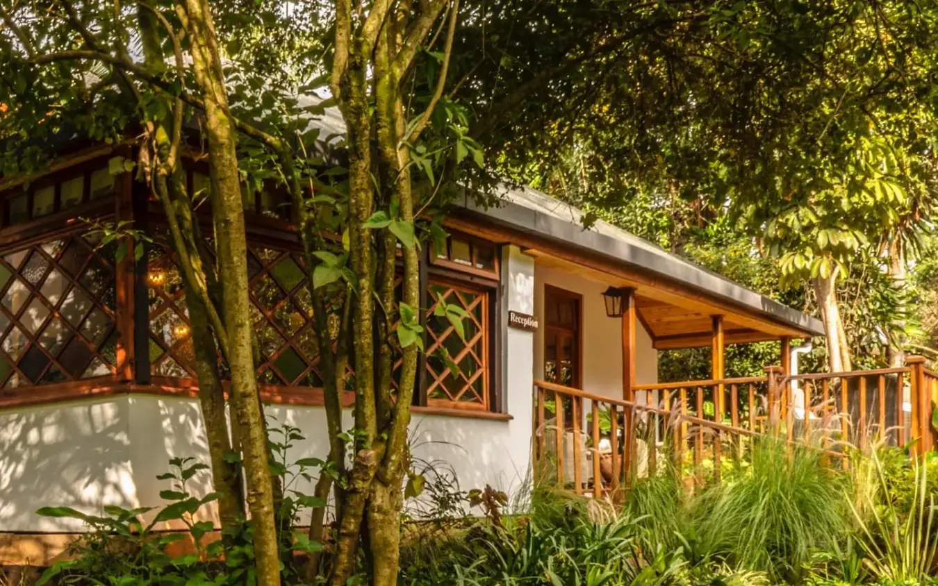 Cottage with wooden veranda surrounded by lush tropical vegetation and vines, Karen Blixen Cottages, Nairobi, Kenya