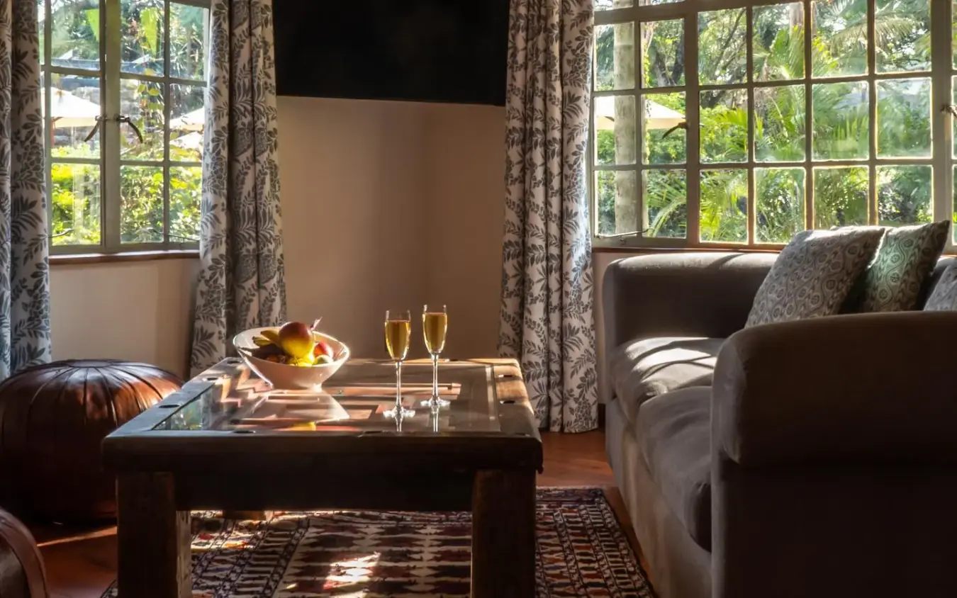Luxury lounge with champagne and fruit bowl overlooking manicured gardens, Karen Blixen Cottages, Nairobi, Kenya