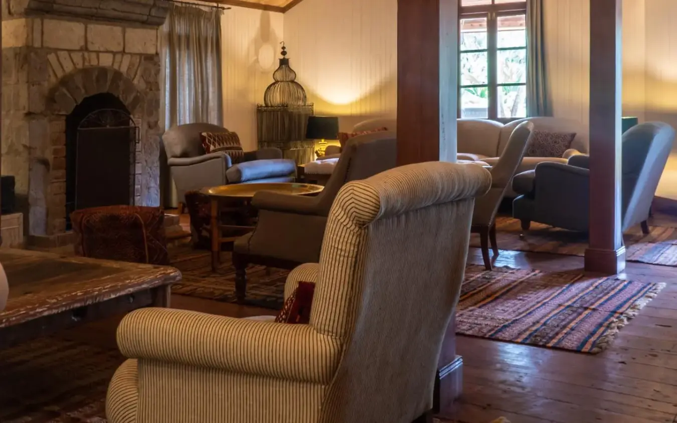 Upholstered wingback chair in luxury lodge lounge with wooden flooring, Karen Blixen Cottages, Nairobi, Kenya