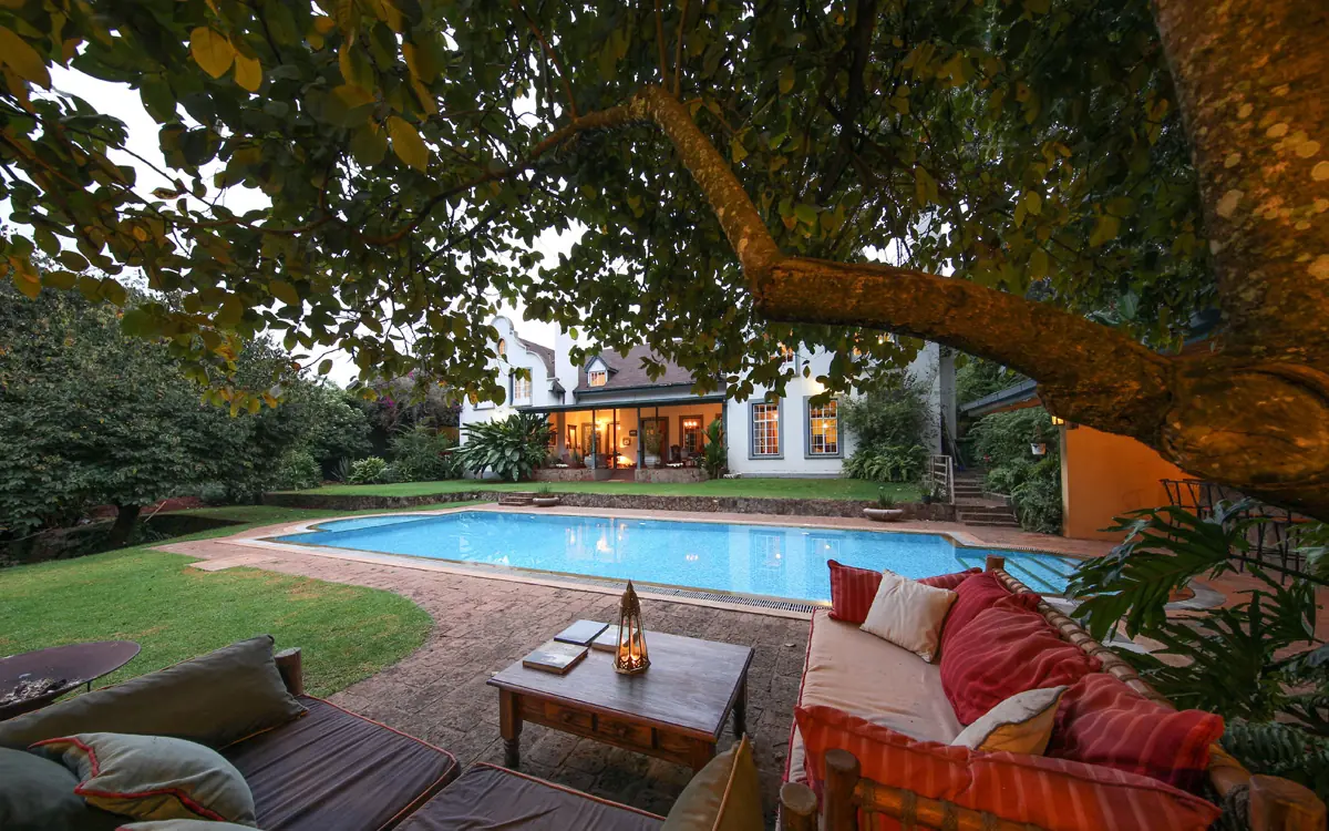 Swimming pool with lounge seating and illuminated house at dusk, Karen Gables, Nairobi, Kenya