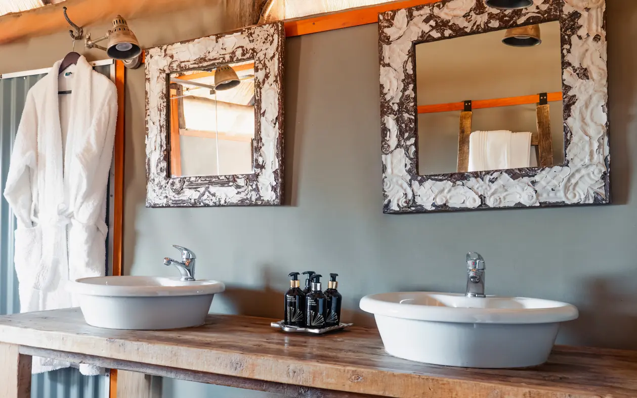 Rustic bathroom vanity with dual vessel sinks and decorative mirrors, Khulu Bush Camp, Hwange National Park, Zimbabwe