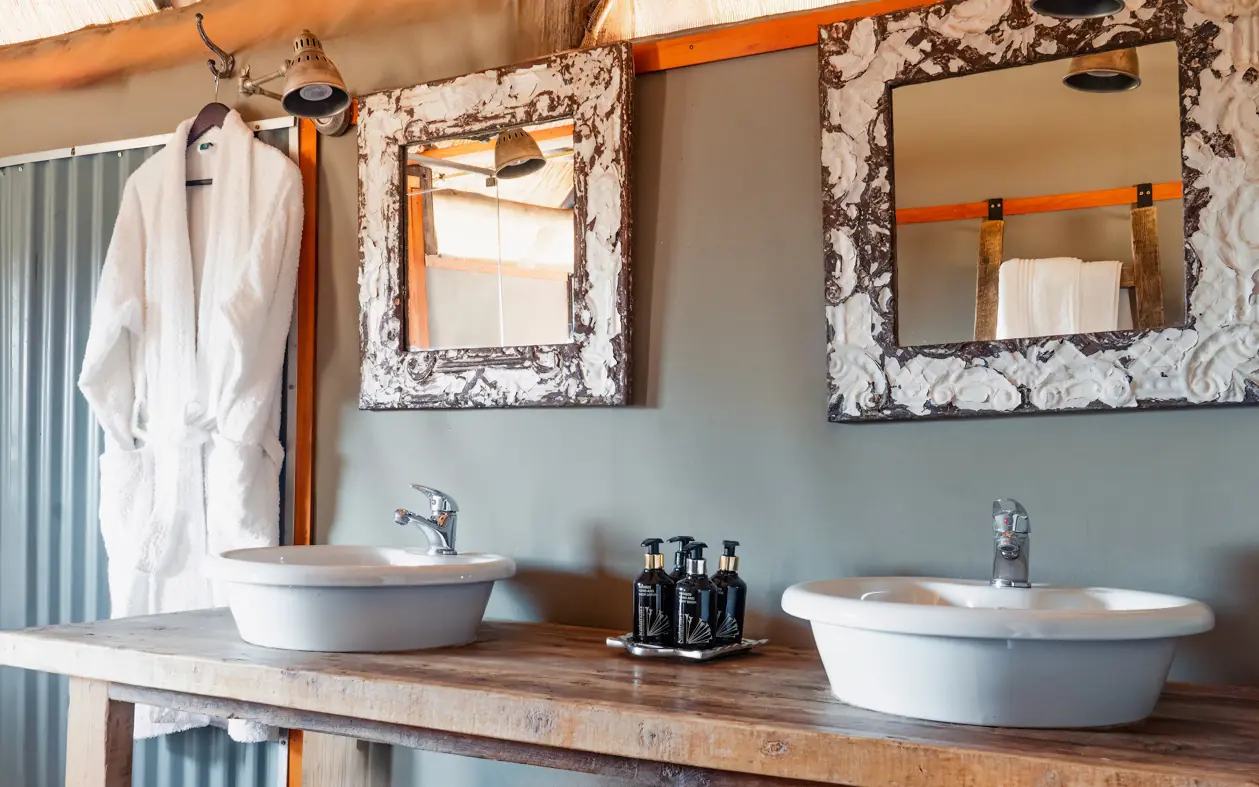Luxury safari lodge bathroom with dual vessel sinks and decorative mirrors, Khulu Bush Camp, Hwange National Park, Zimbabwe
