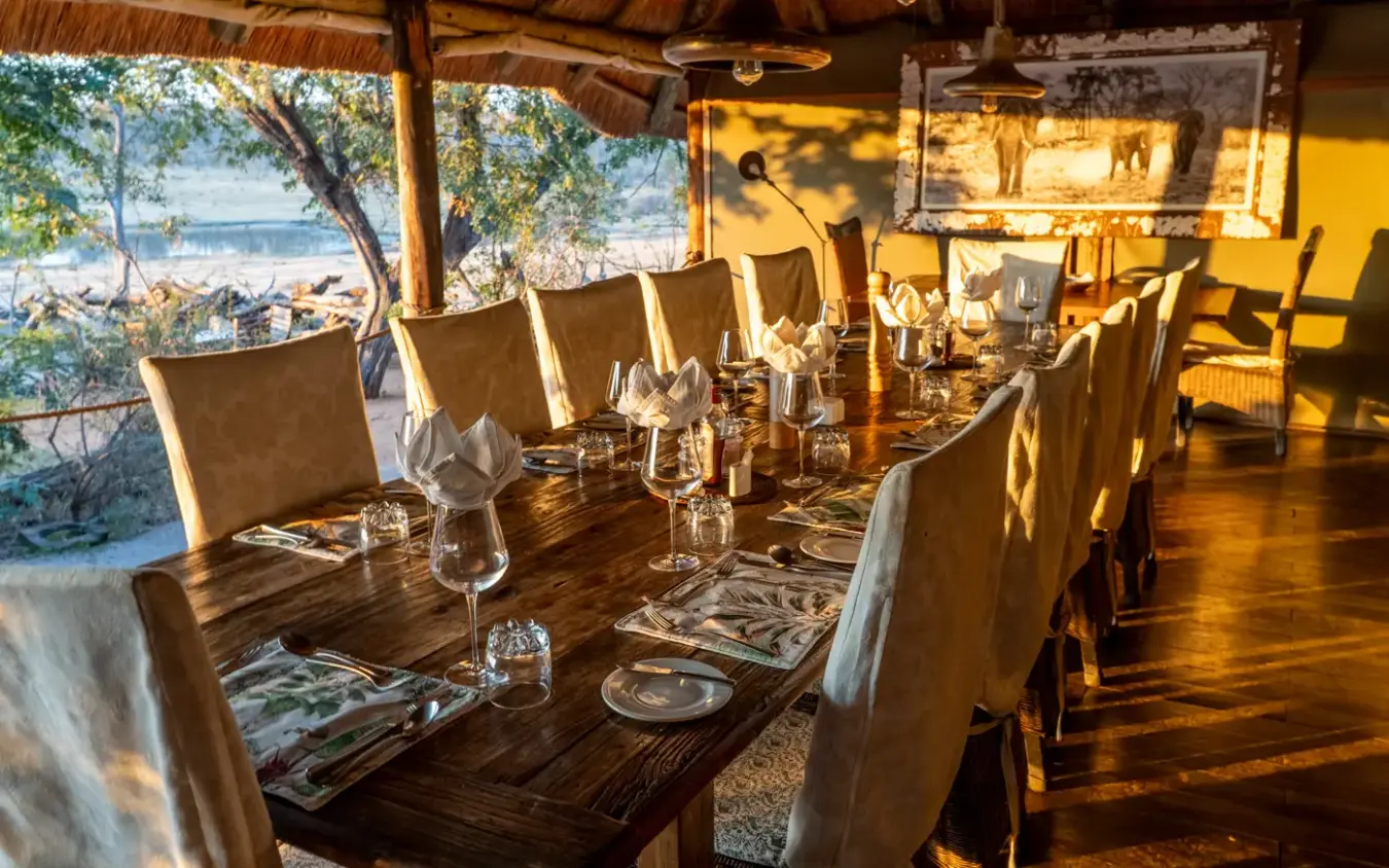 Dining pavilion with long table overlooking waterfront at sunset, Khulu Bush Camp, Hwange National Park, Zimbabwe