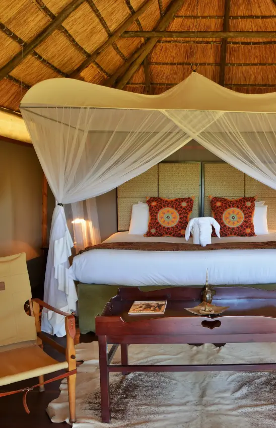 Luxury safari bedroom with sheer canopy and thatched roof interior, Khulu Bush Camp, Hwange National Park, Zimbabwe