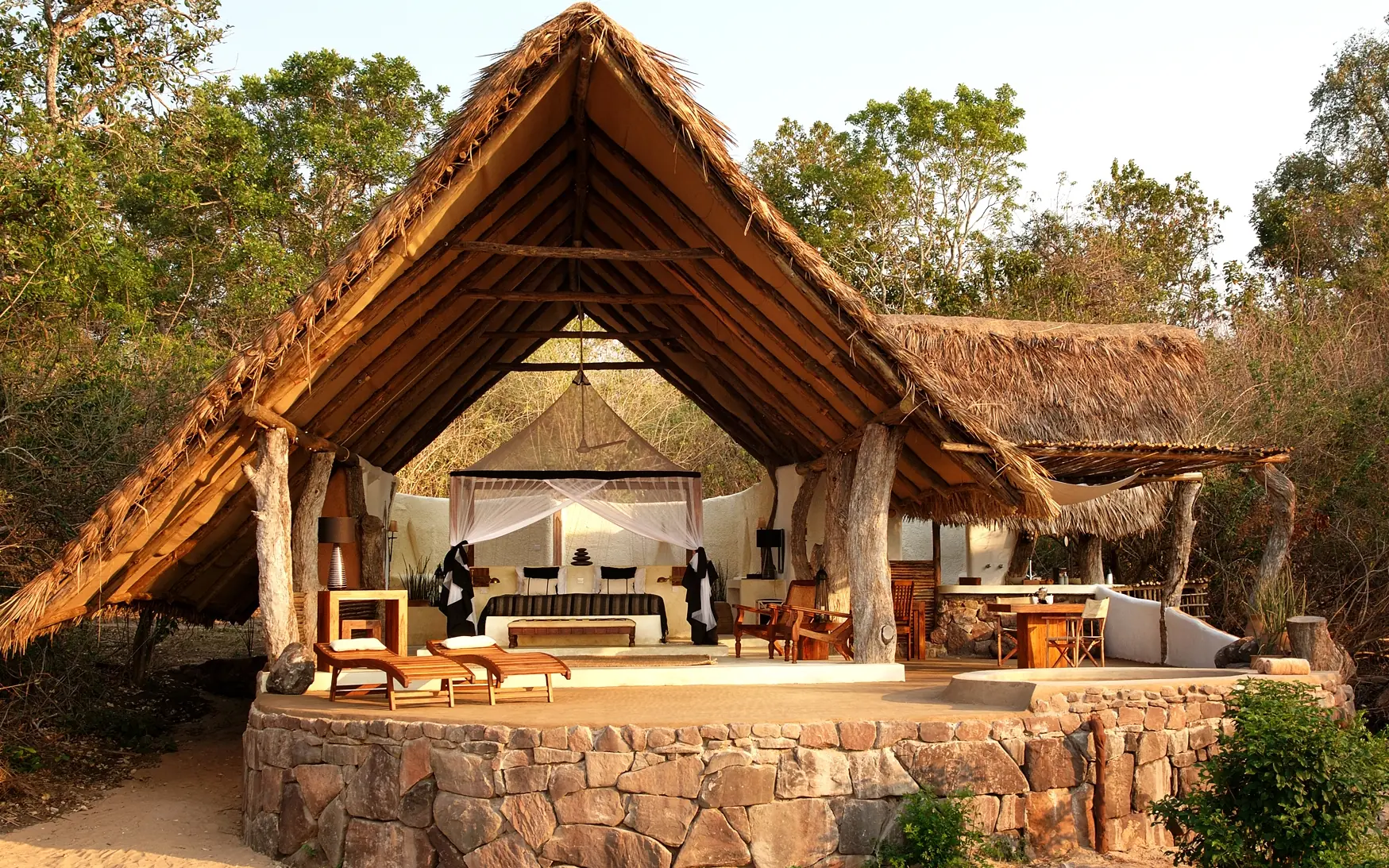 Luxury safari lodge with thatched roof and stone platform among woodland trees, Kiba Point, Nyerere National Park, Tanzania