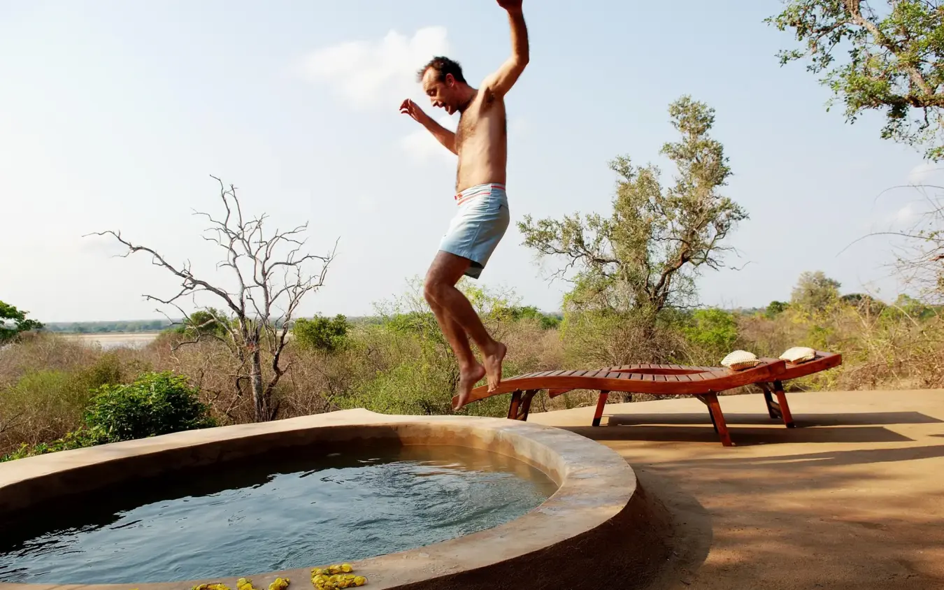Man jumping into circular plunge pool overlooking savanna landscape, Kiba Point, Nyerere National Park, Tanzania