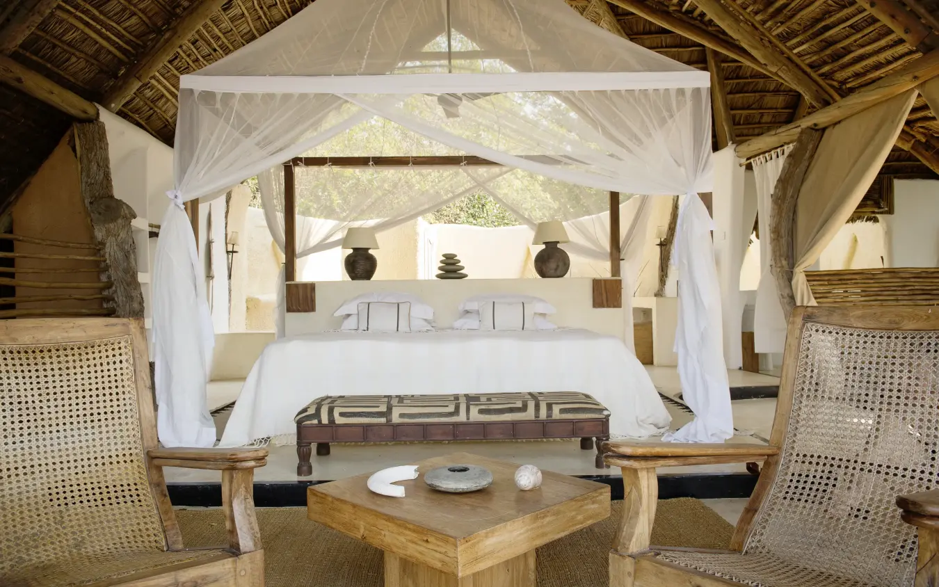 Luxury safari bedroom with four-poster canopy bed and private lounge area, Kiba Point, Nyerere National Park, Tanzania