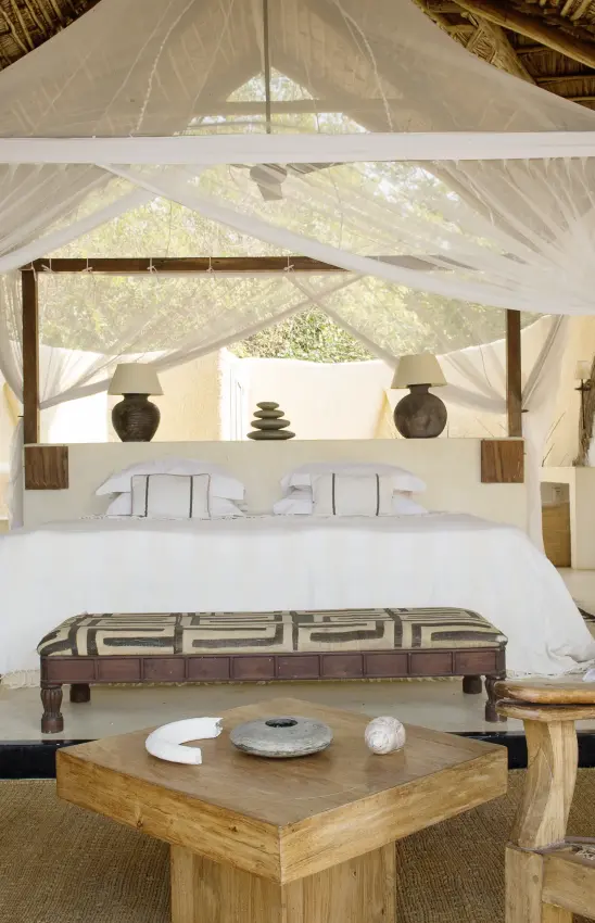 Luxury safari bedroom with sheer canopy drapes and wooden furnishings, Kiba Point, Nyerere National Park, Tanzania